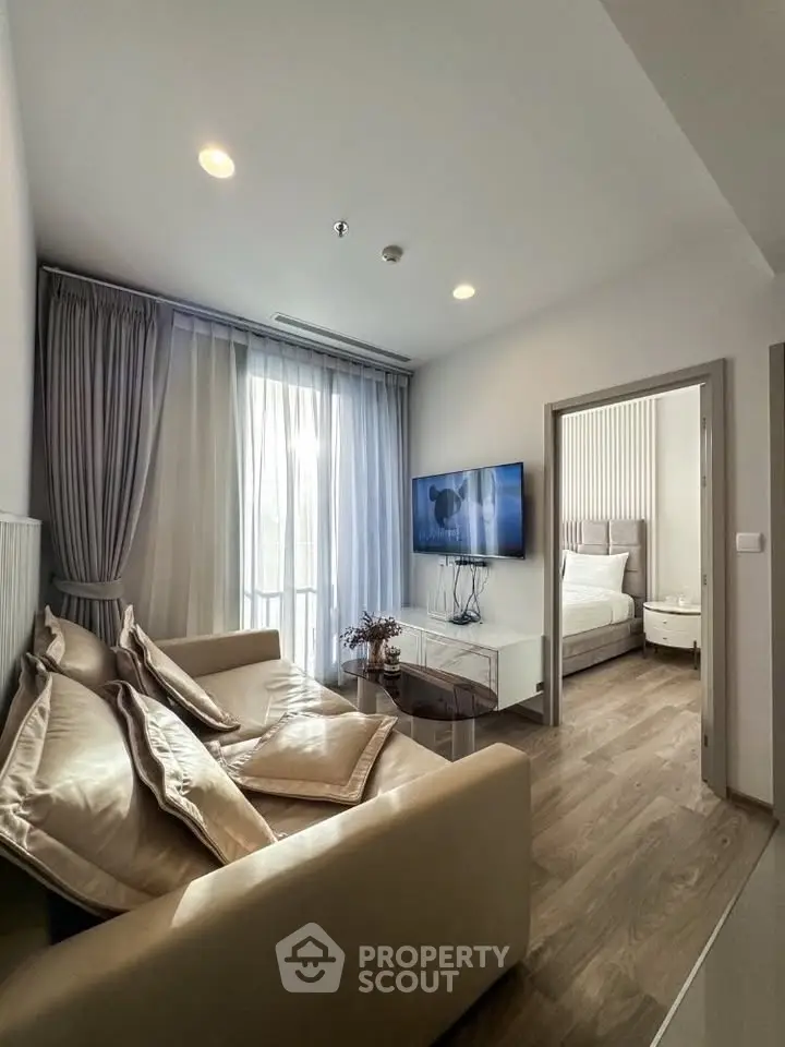 Modern living room with cozy sofa and wall-mounted TV, leading to a stylish bedroom.