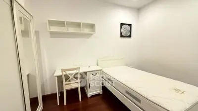 Cozy minimalist bedroom with single bed, desk, and wardrobe in bright white decor.