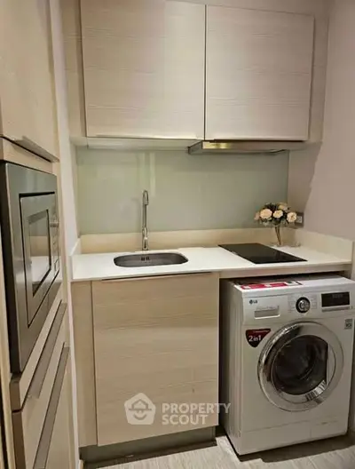 Modern compact kitchen with washing machine and oven, ideal for urban living.