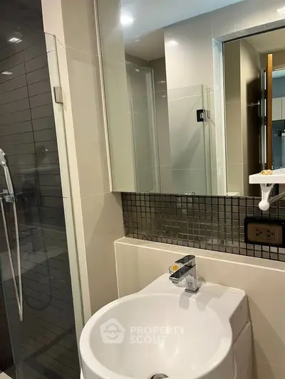 Modern bathroom with sleek fixtures and glass shower enclosure in a contemporary apartment.