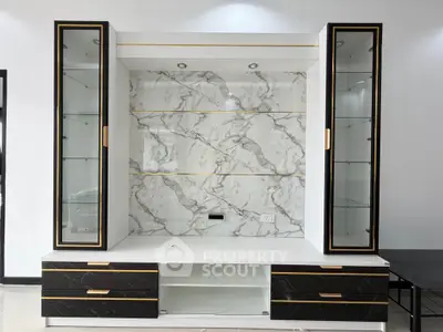 Elegant modern living room cabinet with marble backdrop and glass shelves.