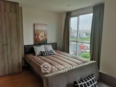 Cozy bedroom with large window offering a stunning city view, modern decor, and ample natural light.