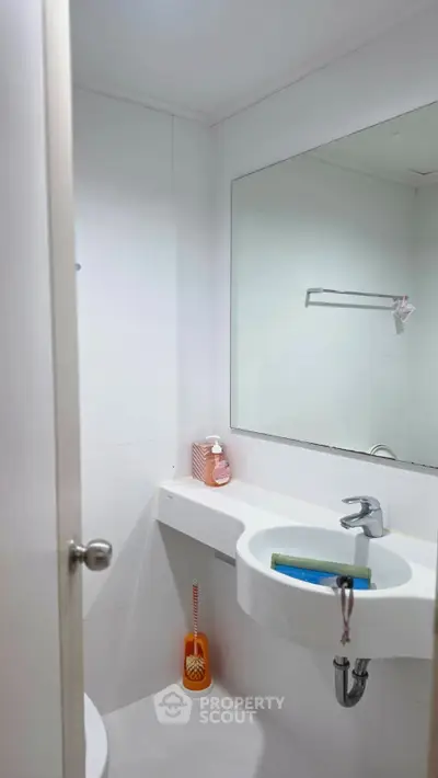 Compact modern bathroom with sleek white fixtures and large mirror