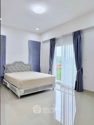 Spacious bedroom with elegant decor and large window offering natural light.