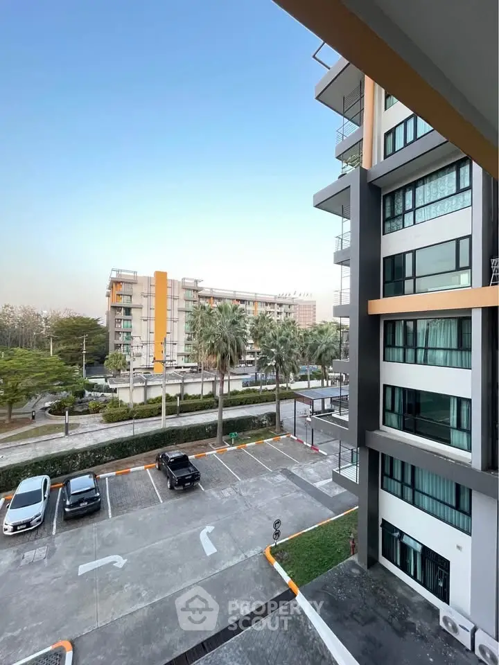 Modern apartment building with parking area and palm trees, showcasing urban living.