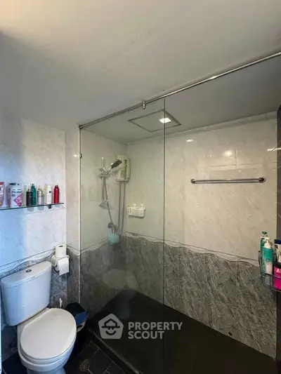 Modern bathroom with glass shower enclosure and marble walls