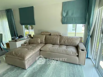 Spacious living room with modern beige sectional sofa and large windows for natural light.