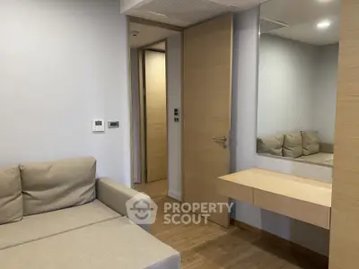 Modern living room with beige sofa and wooden flooring, featuring a sleek wall-mounted desk and mirror.