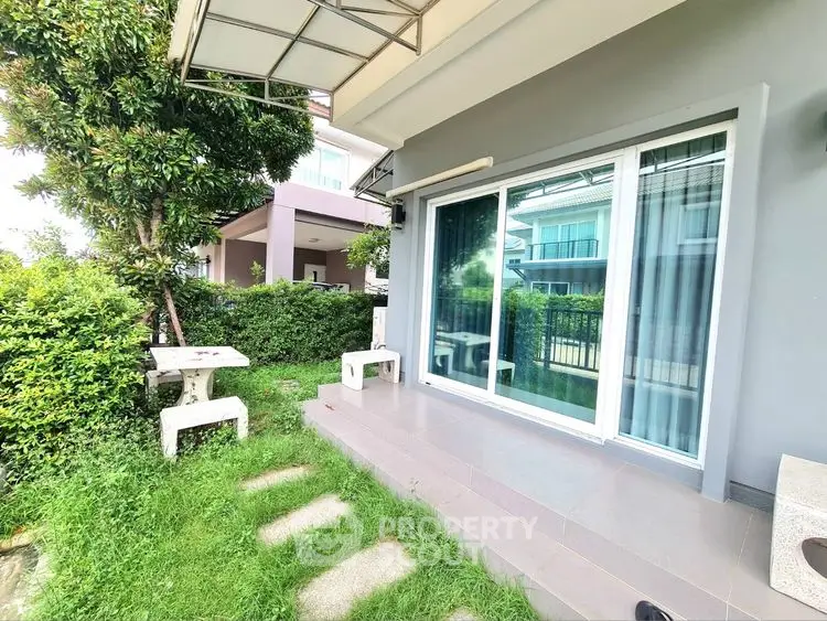 Charming garden view from a modern home's patio with lush greenery.