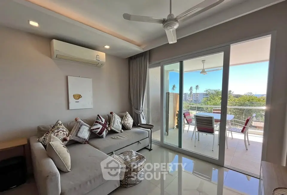 Modern living room with balcony and scenic view, featuring stylish decor and comfortable seating.