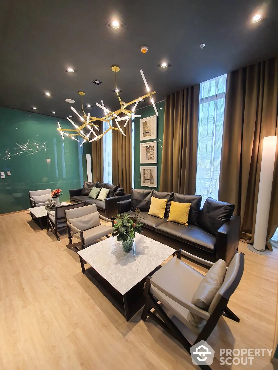 Chic living room with modern art-inspired lighting, sleek black leather sofa, accent cushions, and a statement marble table, complemented by a bold green accent wall and elegant drapery.