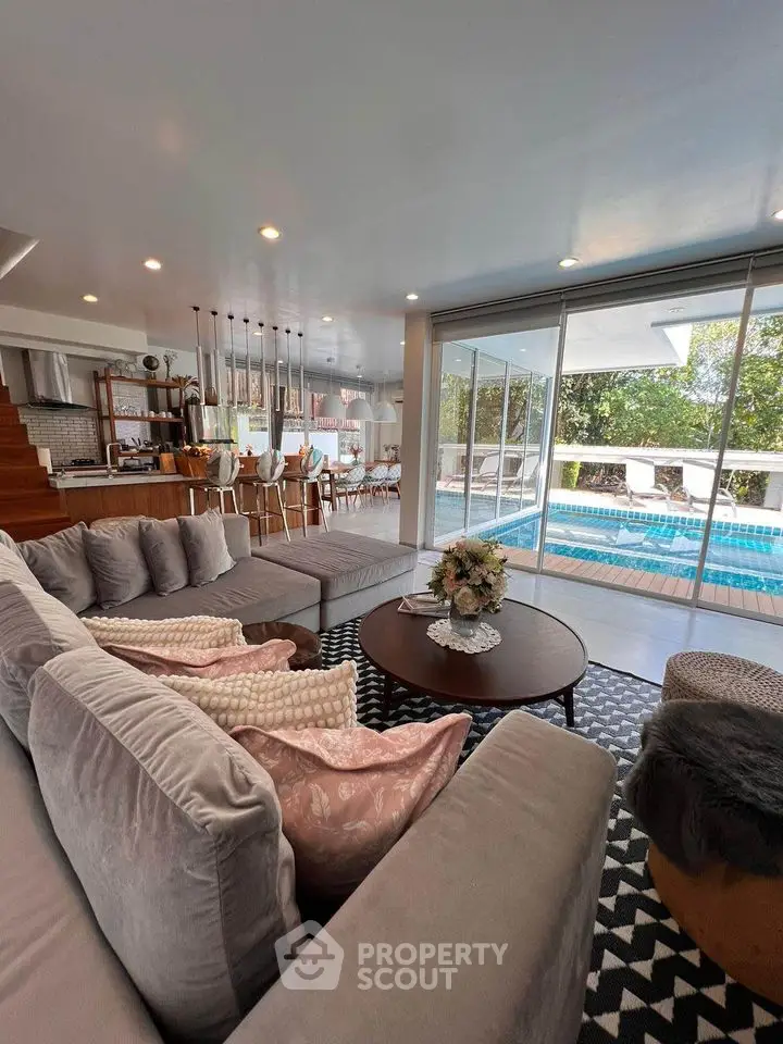 Luxurious living room with pool view and modern open kitchen design
