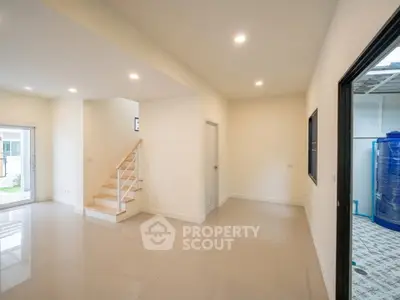 Spacious modern interior with sleek staircase and glossy tiled floors, perfect for contemporary living.