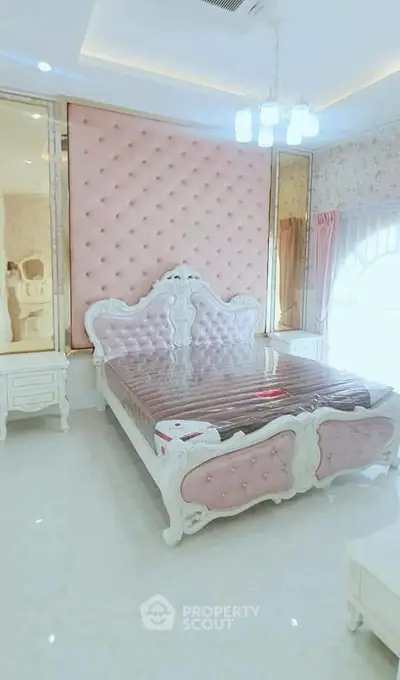 Luxurious bedroom with elegant pink tufted headboard and classic white furniture.