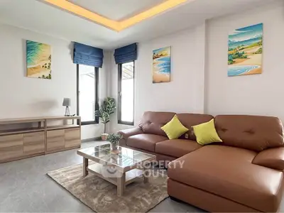 Modern living room with brown sectional sofa and beach-themed artwork