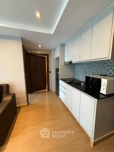 Modern kitchen with sleek cabinetry and microwave in stylish apartment.