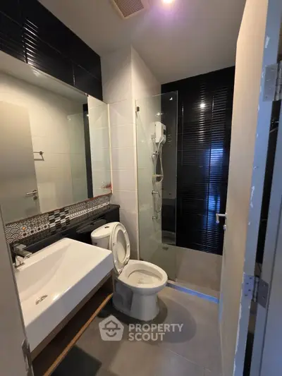 Modern bathroom with sleek design, featuring a glass shower enclosure and stylish sink.