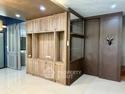 Spacious living area with elegant wooden cabinetry and modern lighting, perfect for stylish urban living.