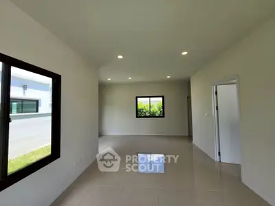 Spacious modern living room with large windows and glossy tiled floors in a contemporary home.