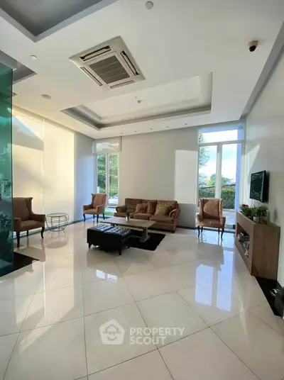 Spacious modern living room with elegant furniture and large windows offering natural light.