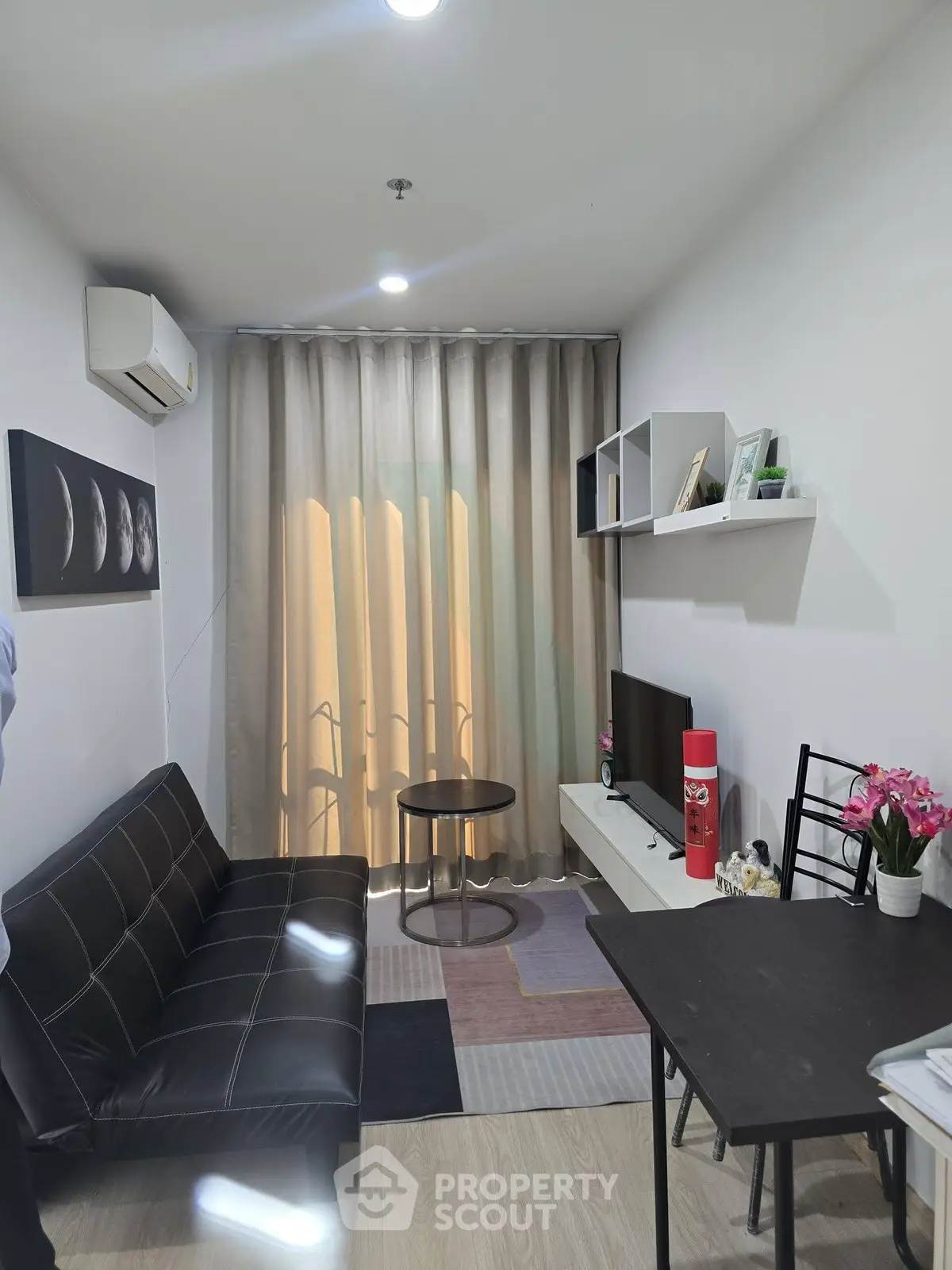 Cozy modern living room with sleek black sofa, wall-mounted TV, and stylish decor.