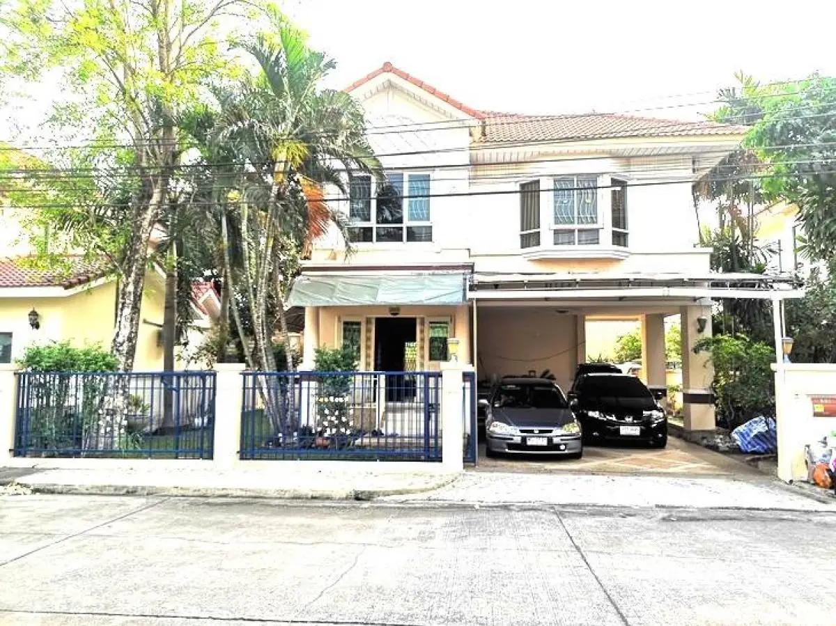 Charming two-story house with carport and lush greenery in a serene neighborhood.