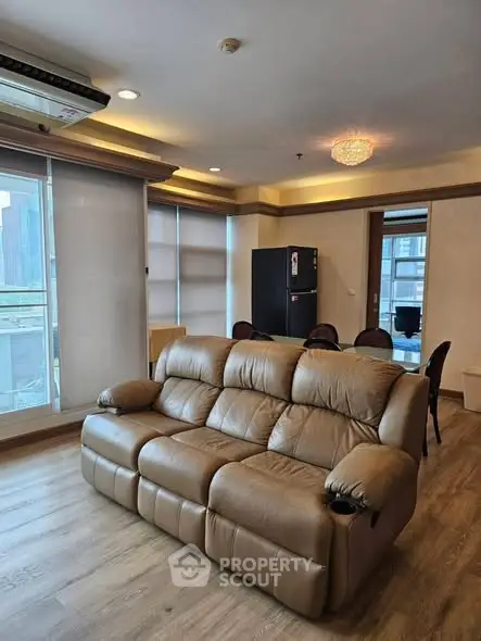 Spacious living room with leather sofa and dining area in modern apartment.