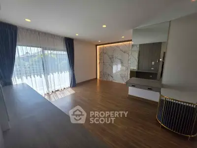 Spacious modern living room with elegant marble accent wall and large windows.