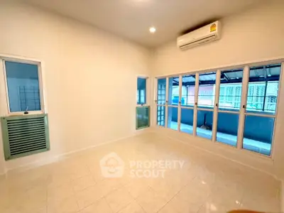 Spacious living room with large windows and air conditioning, perfect for natural light and comfort.