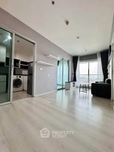 Spacious modern living room with balcony and sleek kitchen appliances in a stylish apartment.
