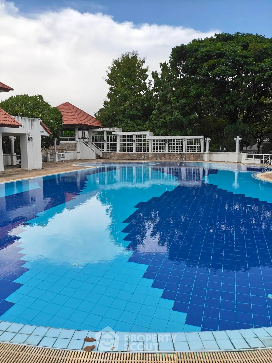 Luxurious outdoor pool area with pristine blue tiles and lush greenery, perfect for relaxation and leisure.