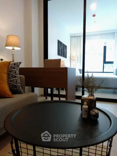 Modern living room with stylish decor and cozy ambiance, featuring a glimpse into a bright bedroom.