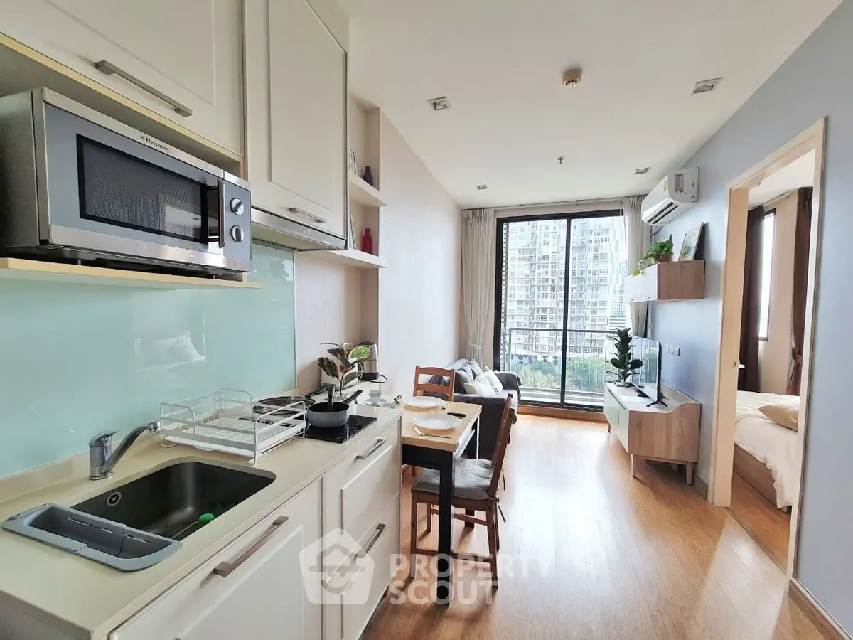 Modern open-layout kitchen and living room with balcony view in a stylish apartment.