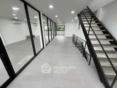 Modern open-plan interior with sleek staircase and large windows, ideal for contemporary living.