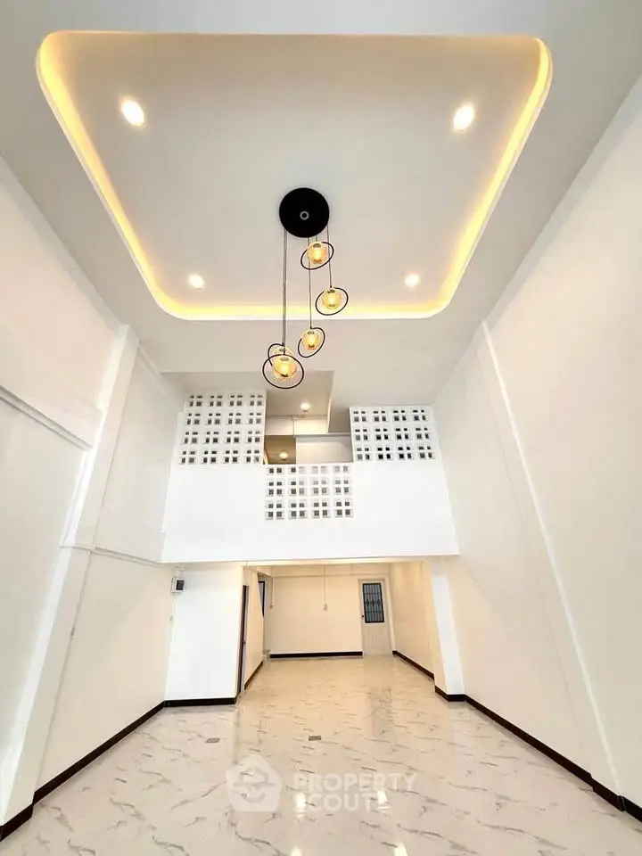 Spacious modern living room with high ceiling and elegant lighting in a contemporary home.