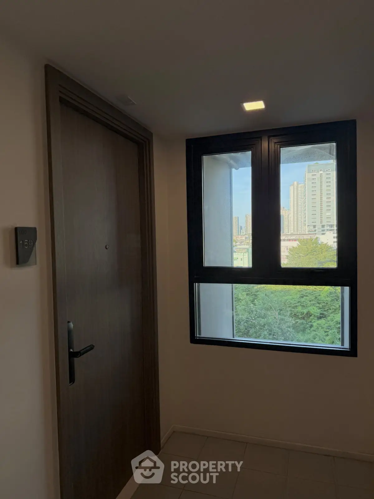 Modern apartment entrance with city view from window, showcasing urban living.