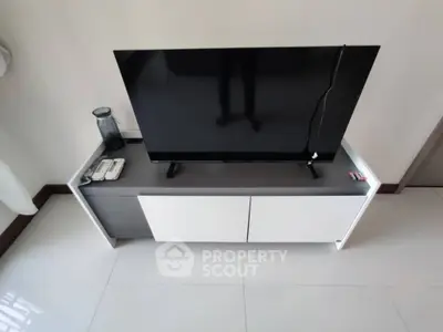 Modern living room with sleek TV stand and flat-screen television, minimalist design.