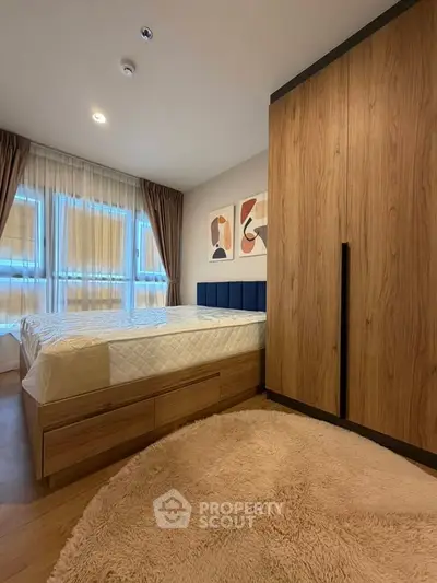 Cozy bedroom with modern wooden wardrobe and plush carpet, featuring large windows for natural light.