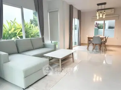 Spacious modern living room with large windows and elegant dining area.