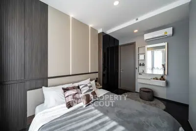 Modern bedroom with stylish decor and ample natural light, featuring a cozy bed and sleek furnishings.
