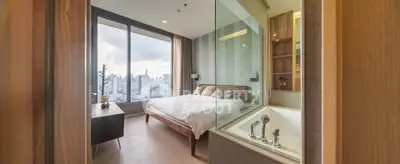 Luxurious bedroom with stunning city view and modern glass-enclosed bathtub.
