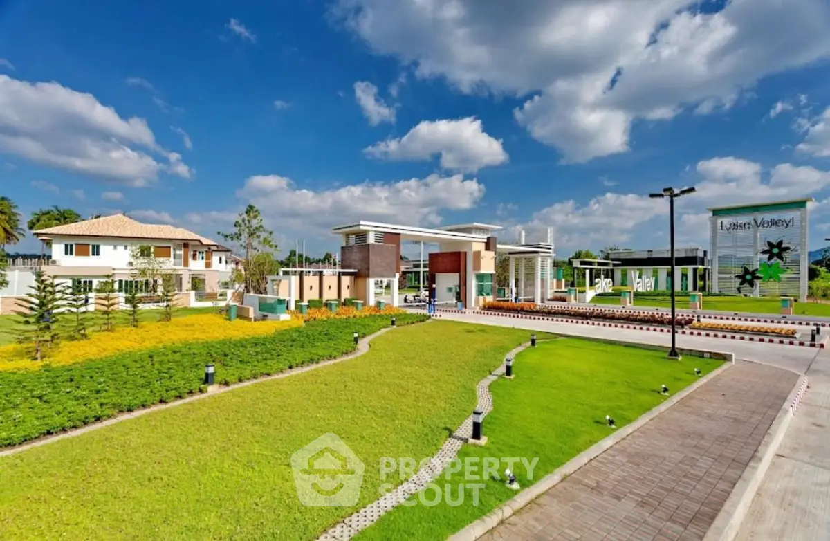 Luxurious modern estate entrance with lush landscaping and clear blue skies.