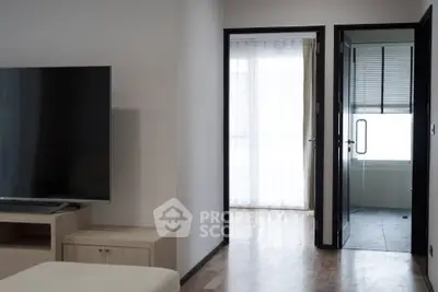 Modern living room with sleek TV and open doorway leading to a bright balcony.