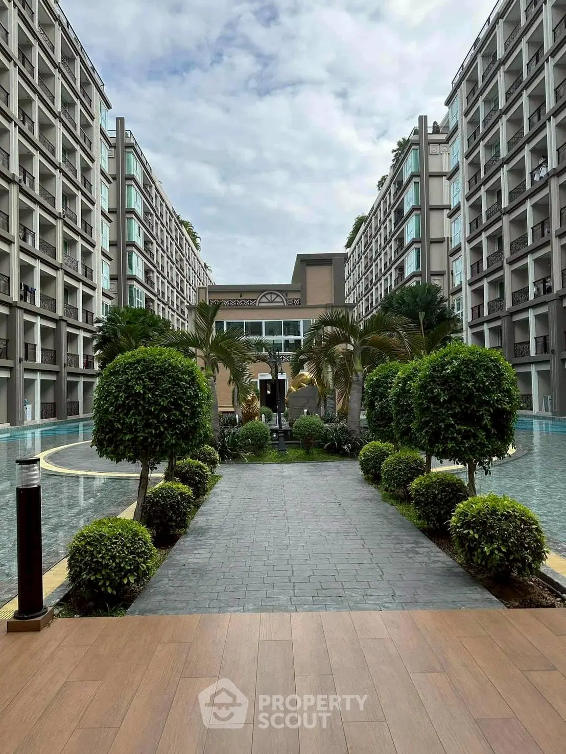 Luxurious modern apartment complex with lush landscaping and water features, offering a serene living environment.