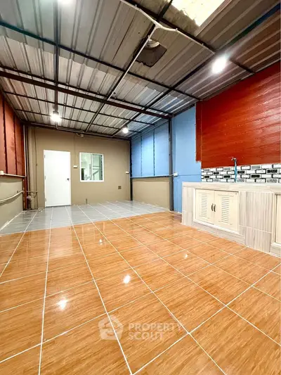 Spacious tiled room with modern kitchenette and ample natural light