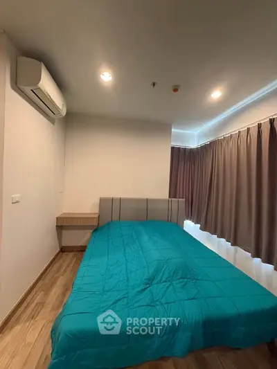Cozy bedroom with modern decor and teal bedding, featuring wooden flooring and air conditioning.