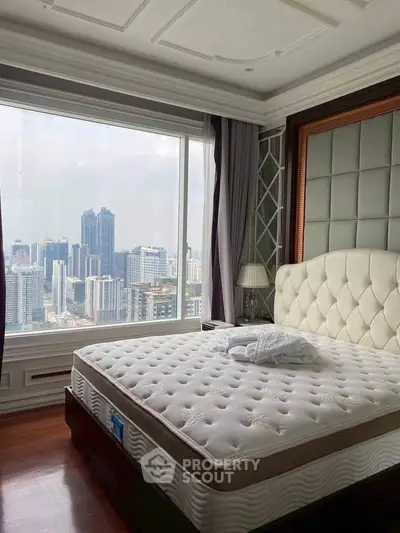 Luxurious bedroom with stunning city skyline view from large window, featuring elegant decor and plush bedding.
