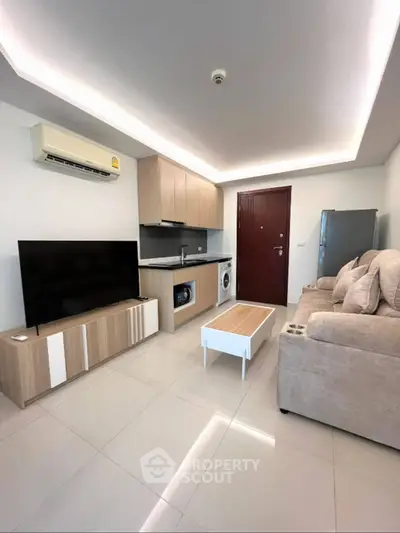 Modern living room with integrated kitchen, featuring sleek appliances and stylish furniture.