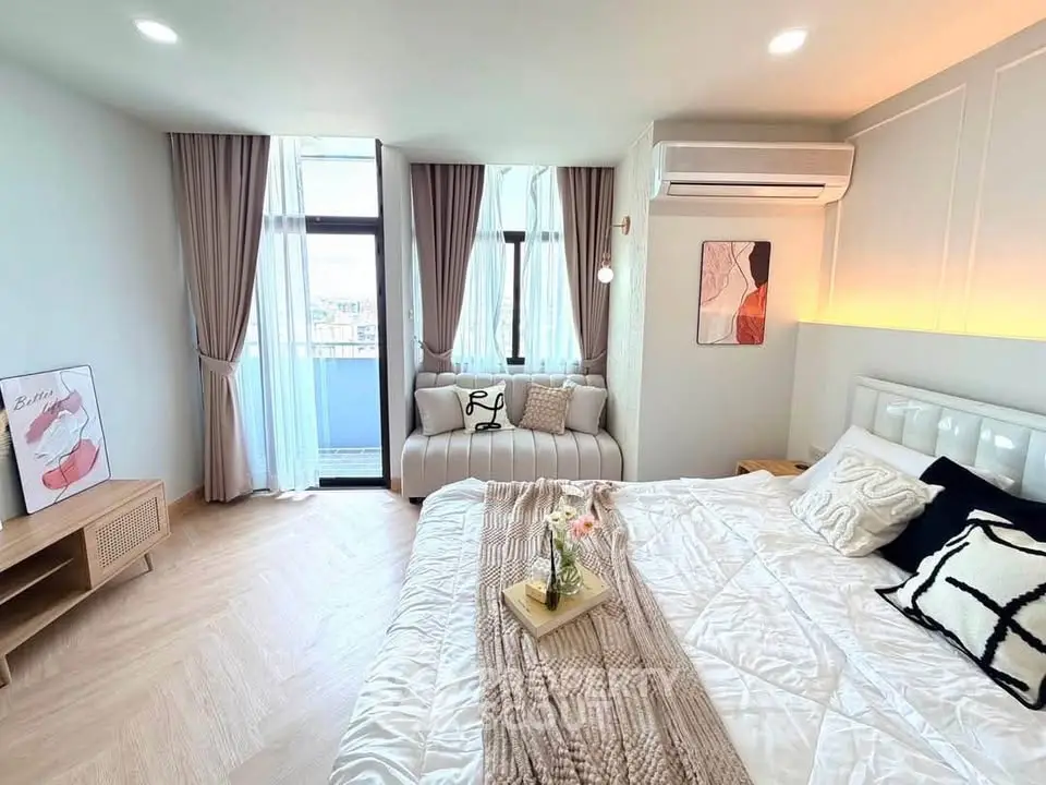 Luxurious bedroom with stylish decor and large windows offering natural light and a cozy seating area.
