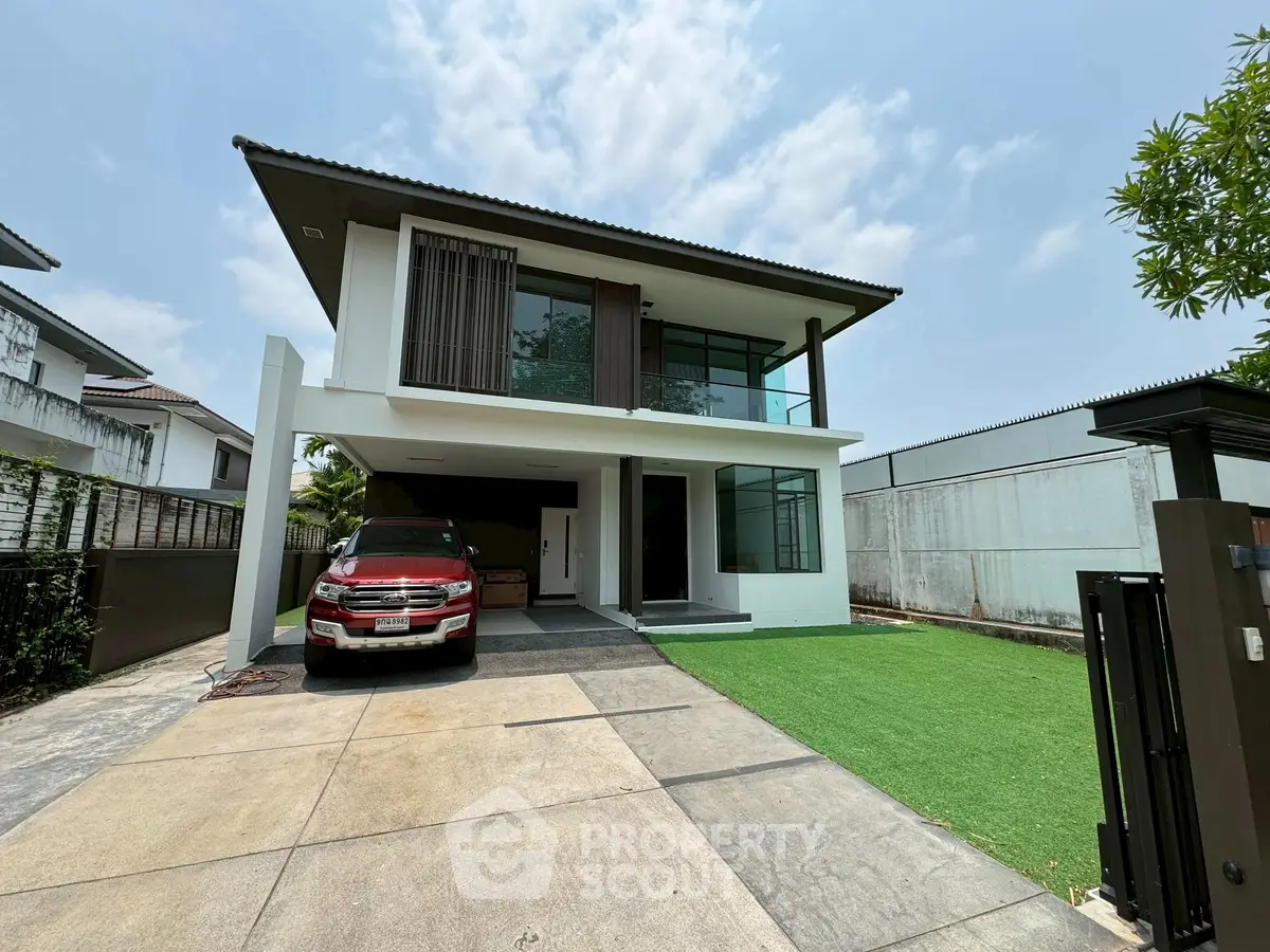 Modern two-story house with driveway and car, featuring sleek design and spacious outdoor area.